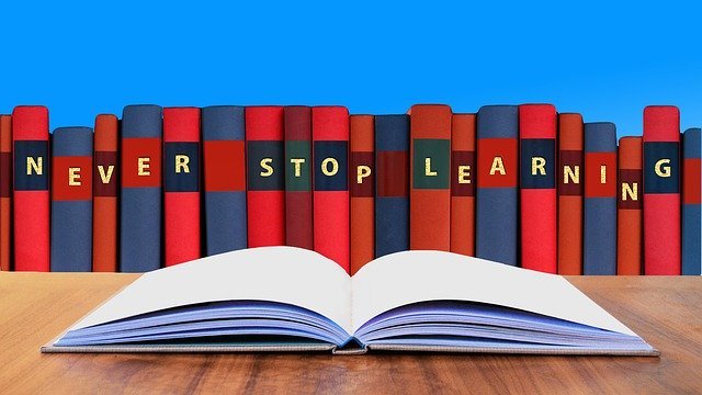 Livre ouvert avec des livres en fond écrient : NEVER STOP LEARNING