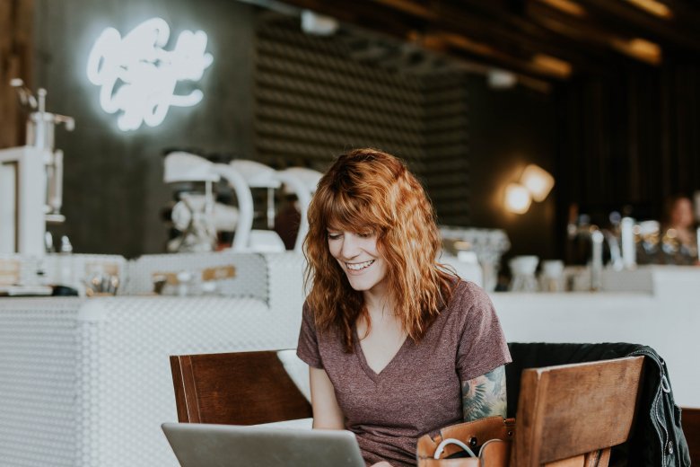 jeune femme souriante consultant un ordinateur dans un café